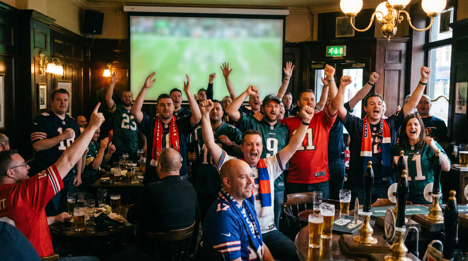 British NFL fans in team jerseys celebrating during a London game broadcast