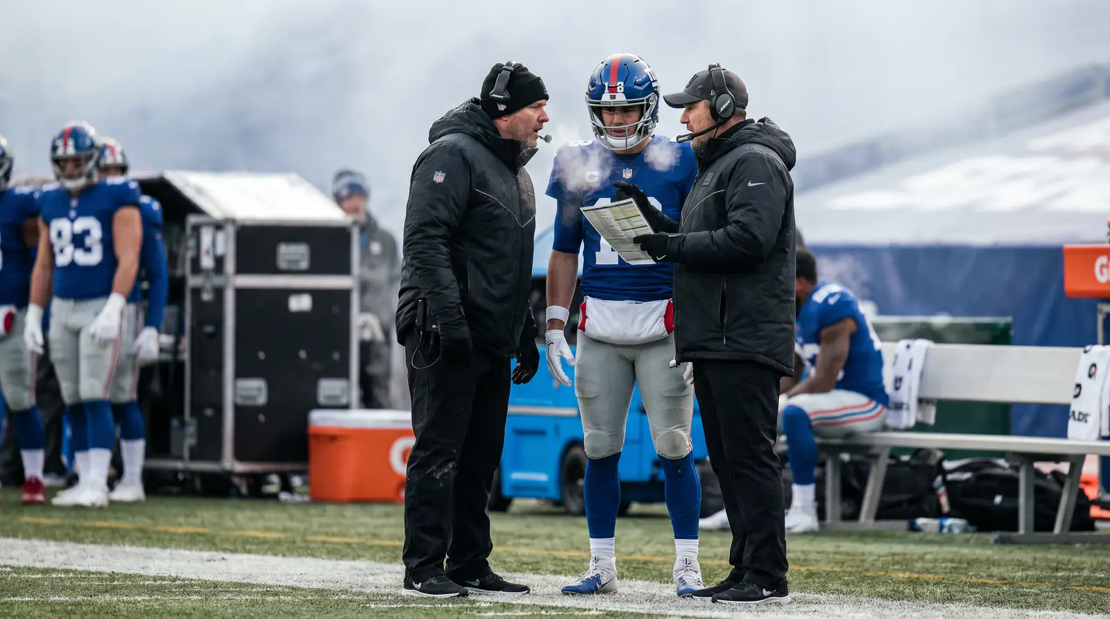 American football coaching staff and players on a sideline conferring during a game