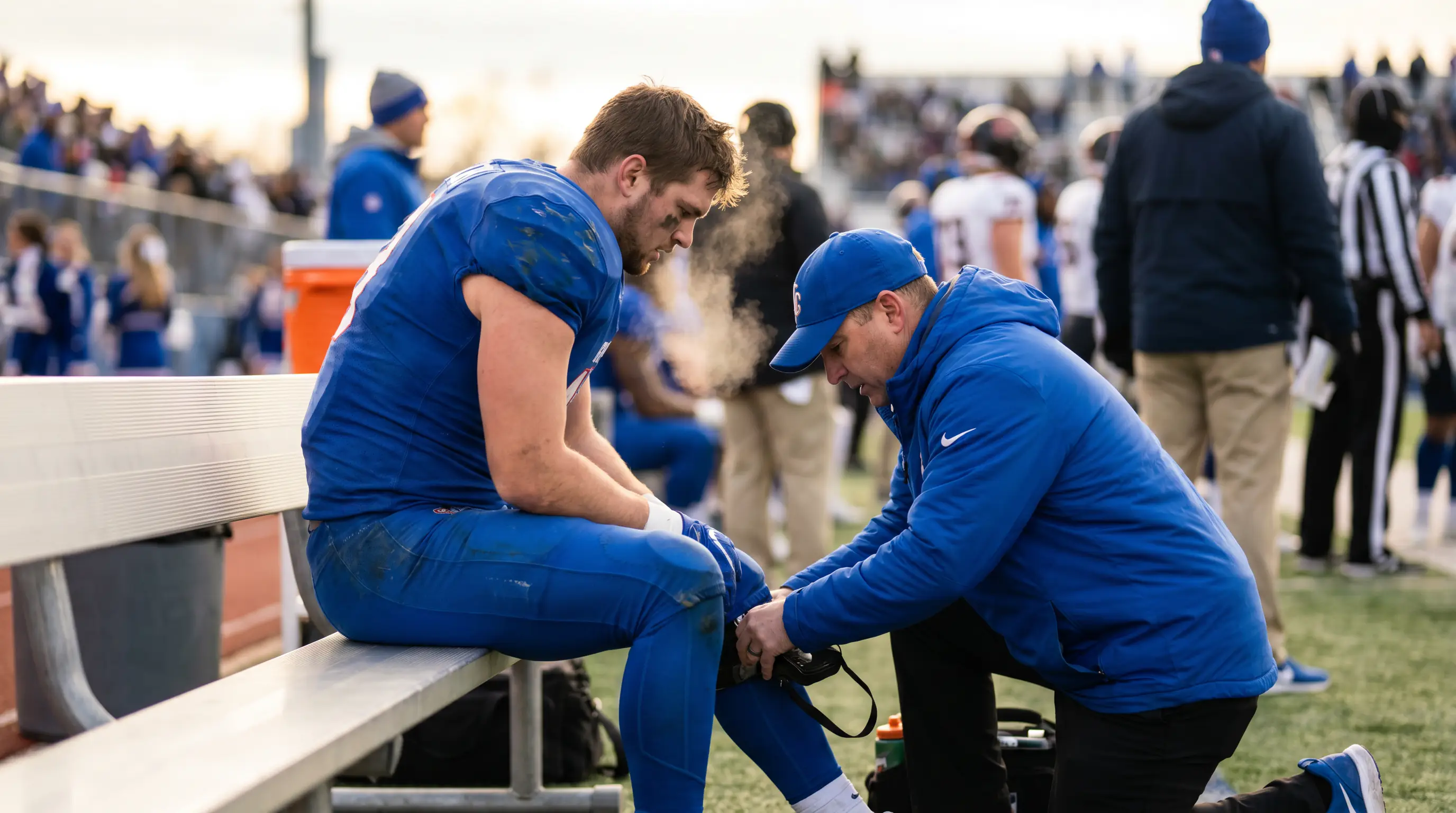 NFL trainer attending to an American football player on the sideline with the team doctor