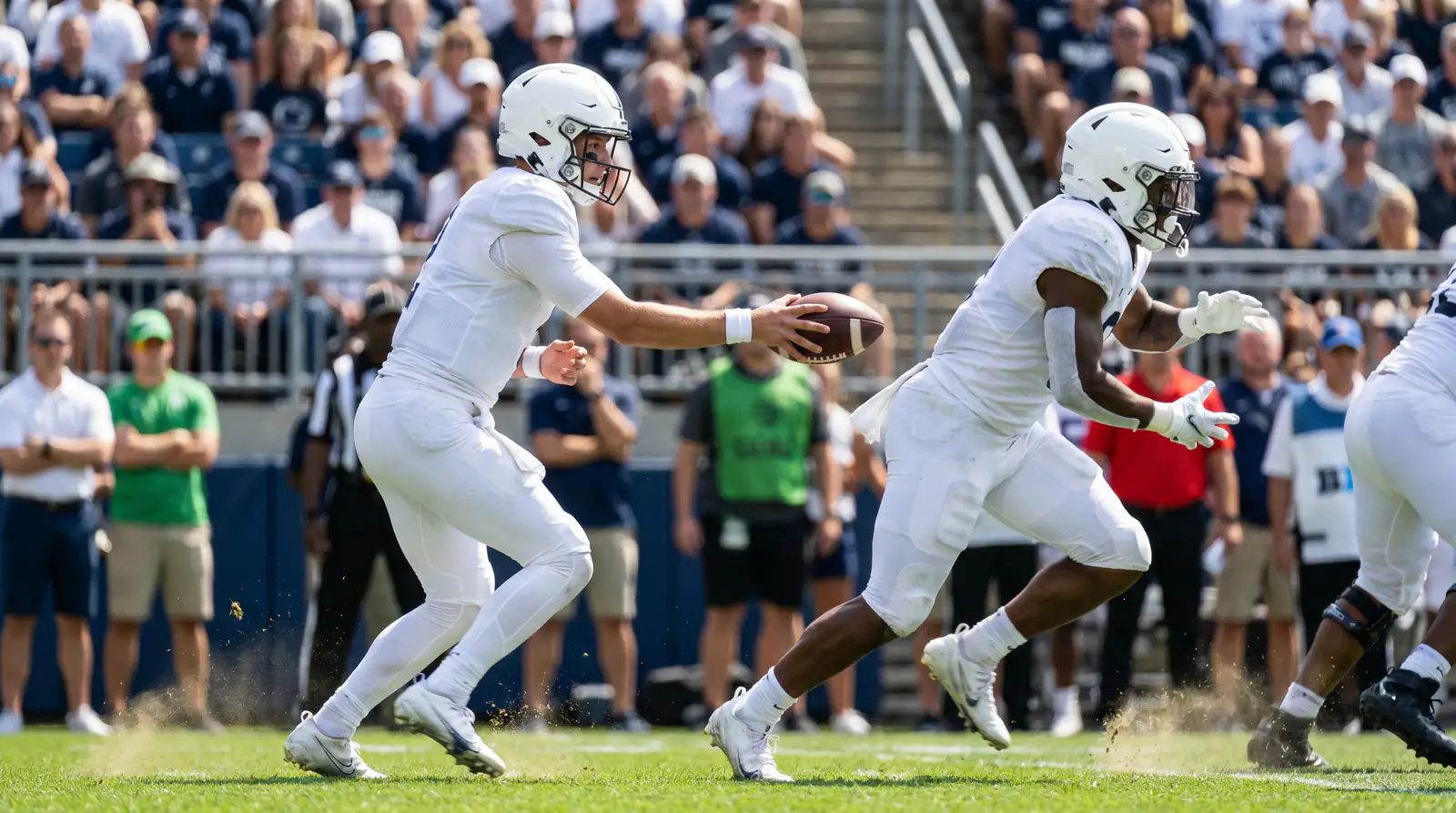 American football quarterback handing the ball off to a running back at the line of scrimmage