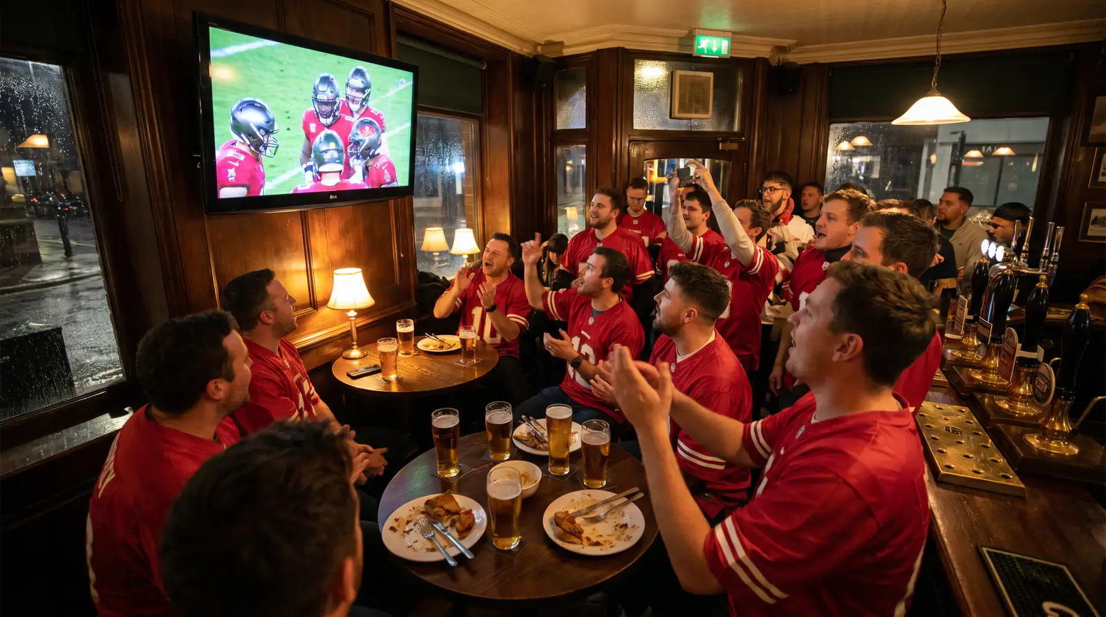 Cluster of UK NFL fans in red kits watching the Chiefs in a British sports bar on a Sunday night